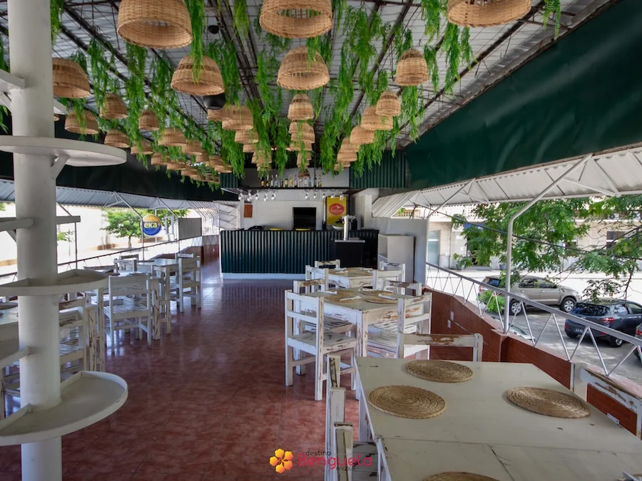 Sala de jantar com mesas brancas e teto decorado com plantas