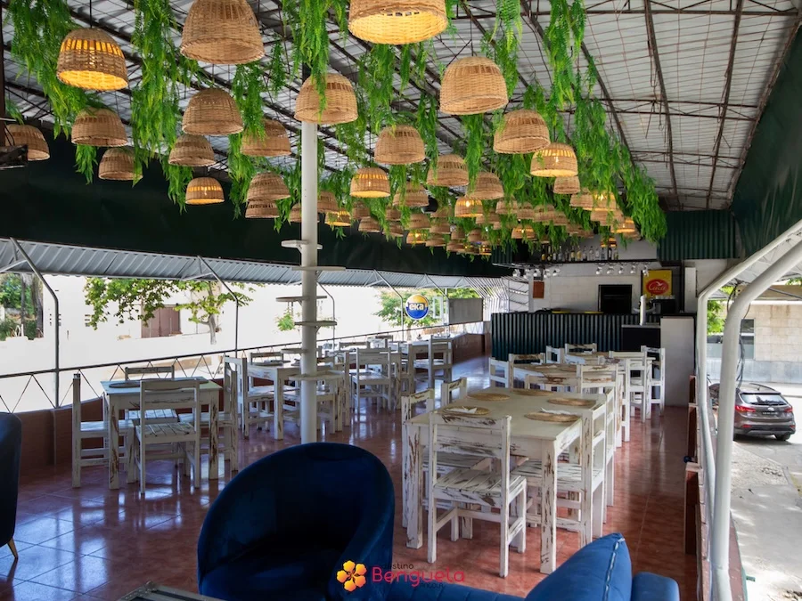 Mesas brancas e cestos de vime pendurados no interior do restaurante